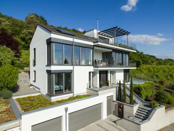 Großzügige Fensterfassade in Holz-Alu mit teilweise sichtbaren Raffstorekästen